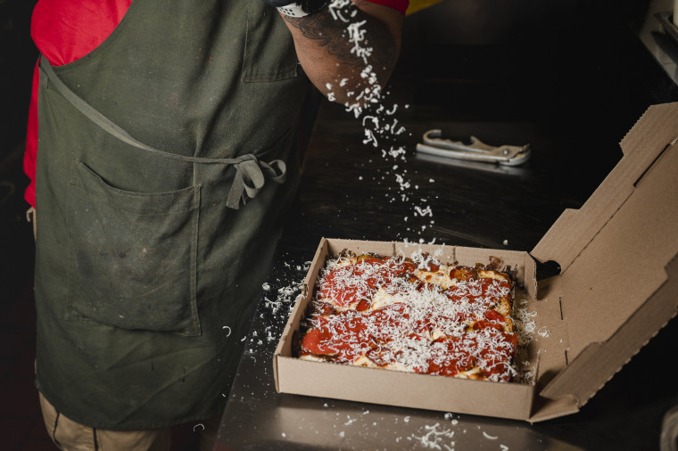 Down North Pizza executive chef Michael Carter grates cheese on the Roc the Mic pizza